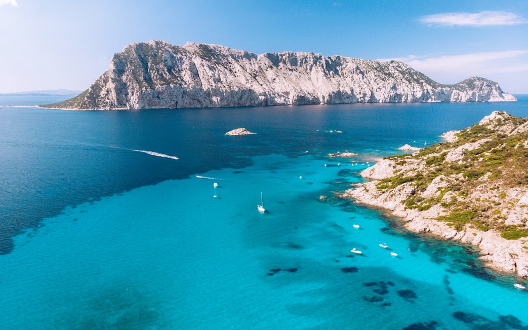 Aerial view of Tavolara Island with boats in turquoise waters, Sardinia, Italy.