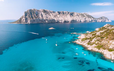 Aerial view of Tavolara Island with boats in turquoise waters, Sardinia, Italy.
