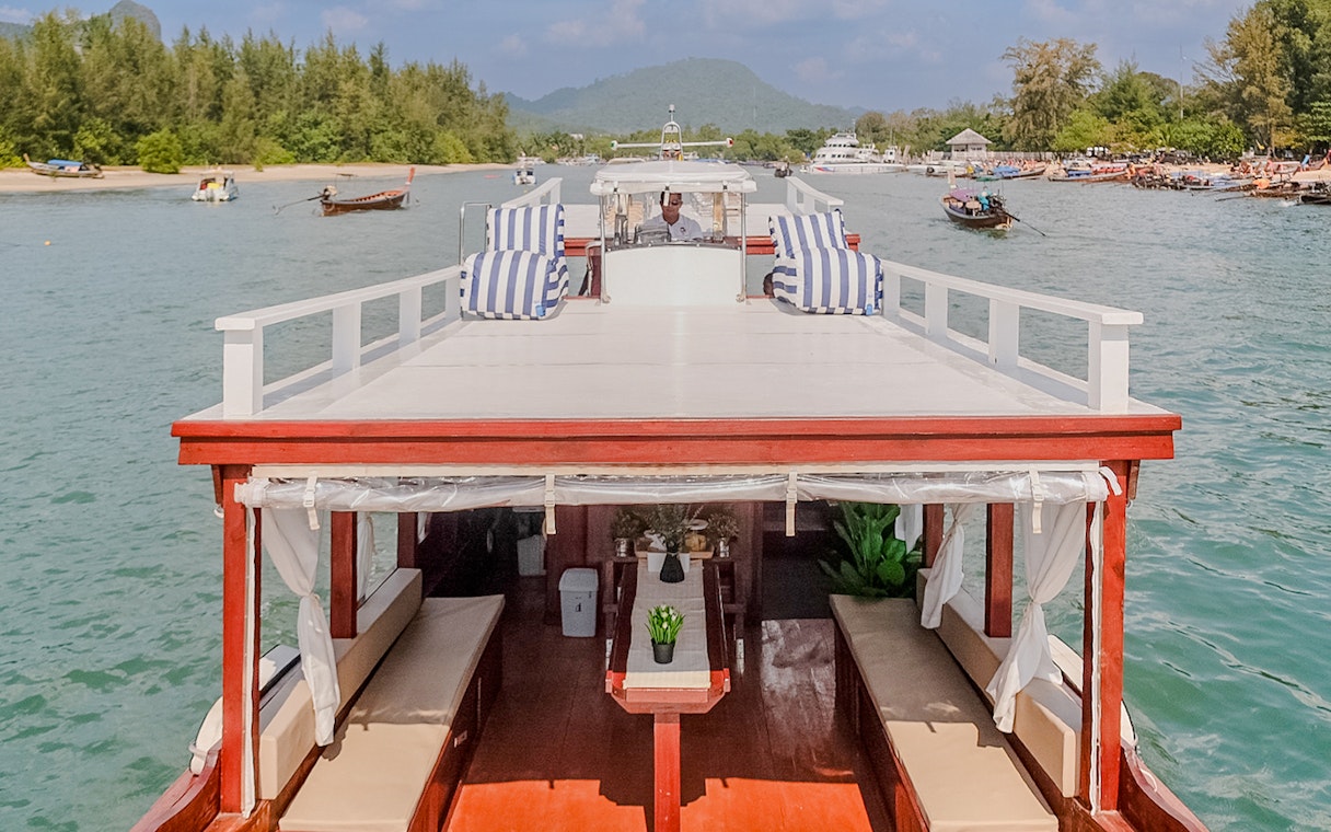 Upper deck of a long tail boat in Krabi with striped cushions and scenic view.