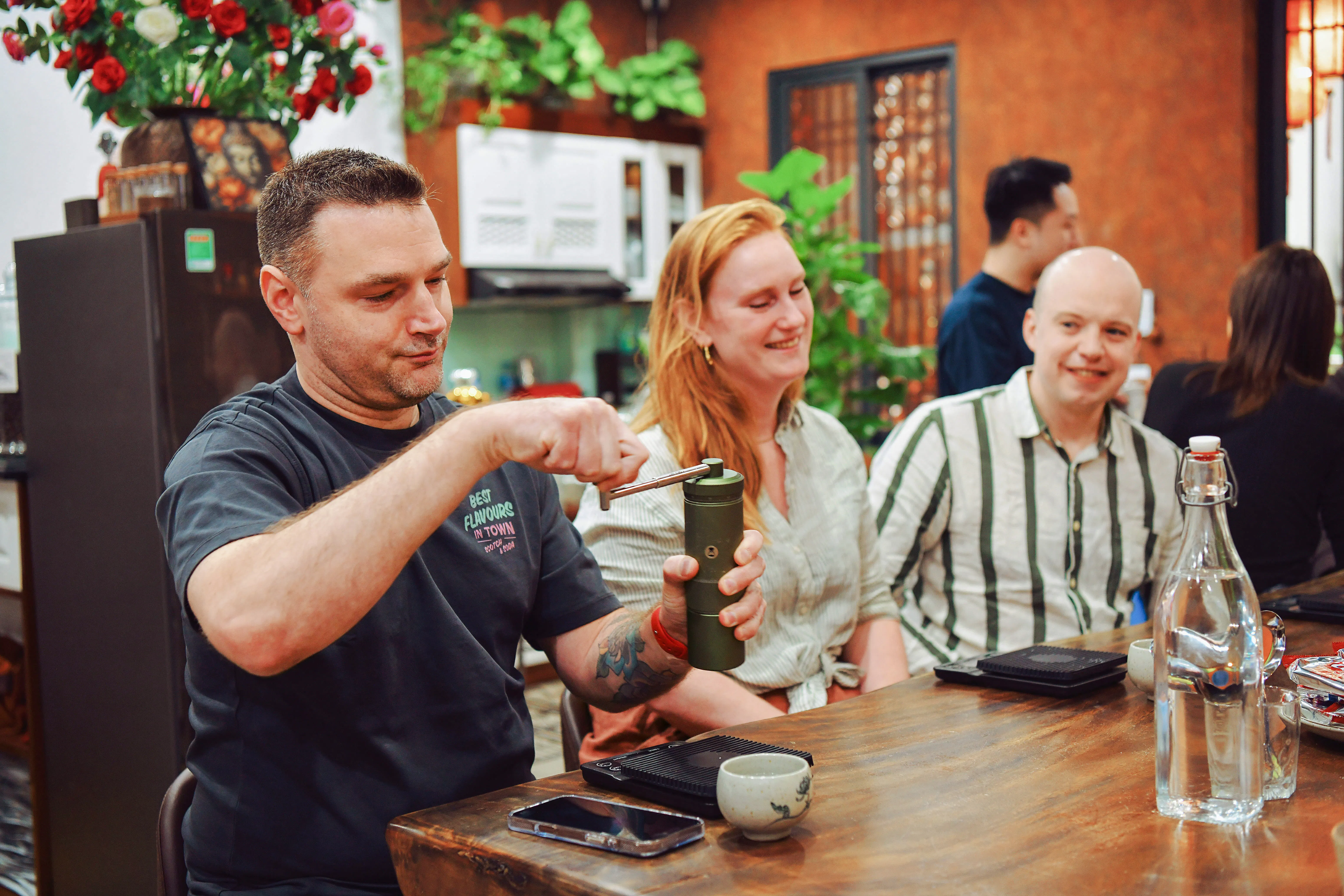 Participants at Hanoi coffee workshop preparing brew with manual grinder.