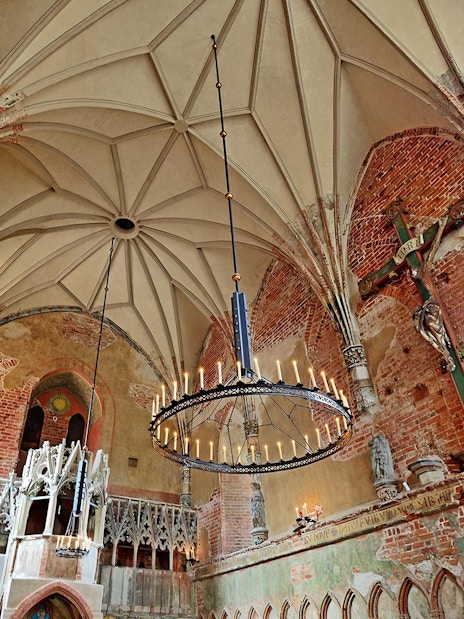Interior of Malbork Castle chapel with brick walls and vaulted ceiling, seen on a tour from Gdańsk.