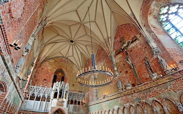 Interior of Malbork Castle chapel with brick walls and vaulted ceiling, seen on a tour from Gdańsk.