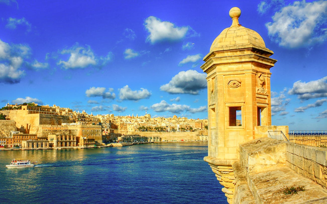 View of Valletta from Sliema with a boat cruising Malta's harbor.