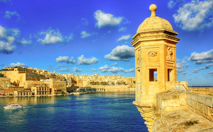 View of Valletta from Sliema with a boat cruising Malta's harbor.