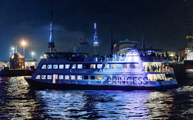 Large ship illuminated at night during 1.5h Grand Evening Lights Cruise.