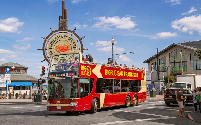 Big Bus San Francisco tour at Fisherman's Wharf with passengers on the open-top deck.