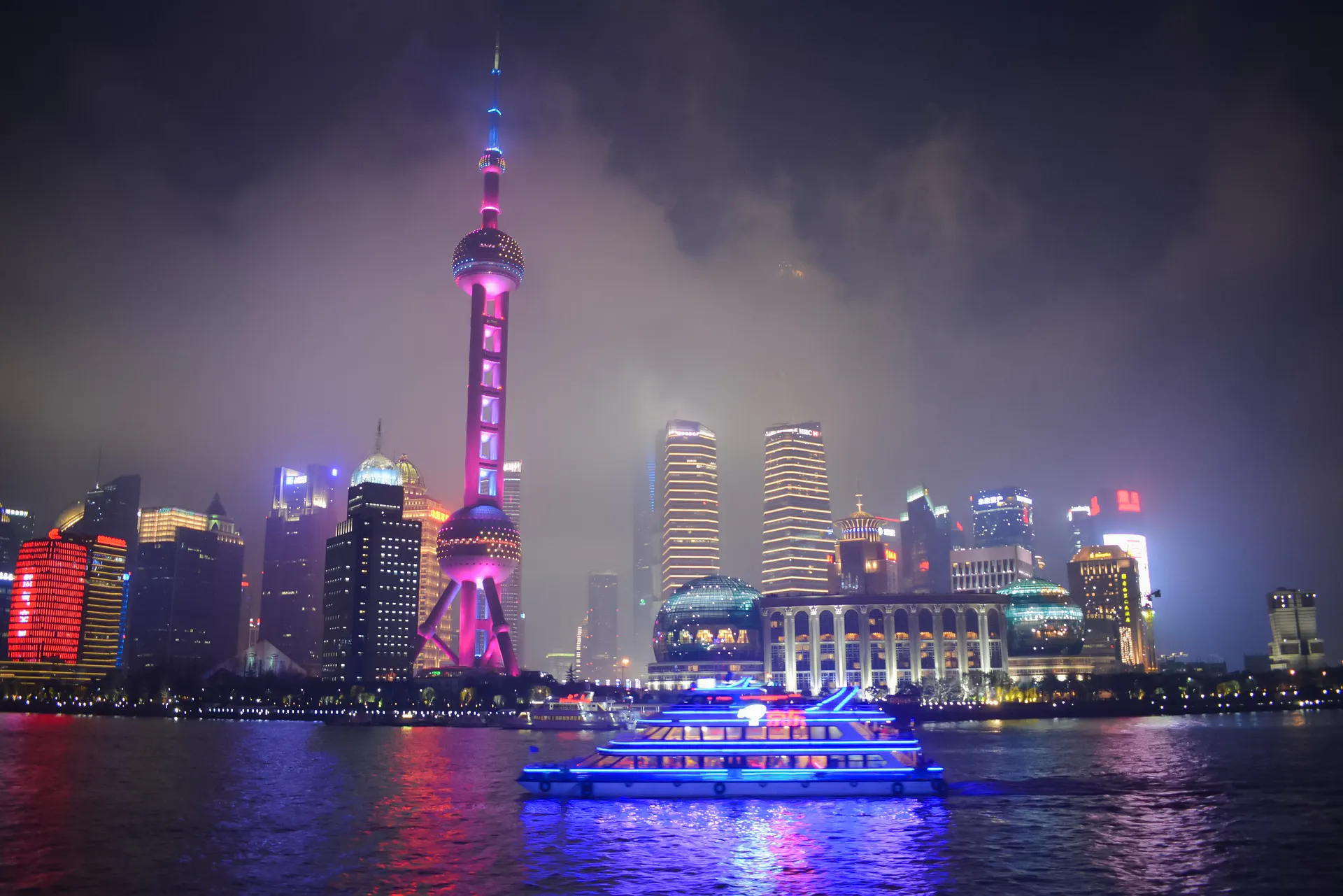 Shanghai Oriental Pearl Tower illuminated at night with a boat on the Huangpu River.