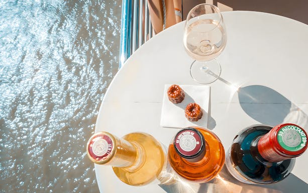 Bottles of wine and canelés on a table during Bordeaux River Cruise.