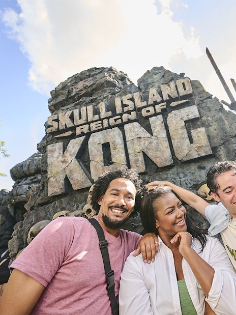 Guests smiling in front of Skull Island: Reign of Kong entrance at Universal Studios Orlando.