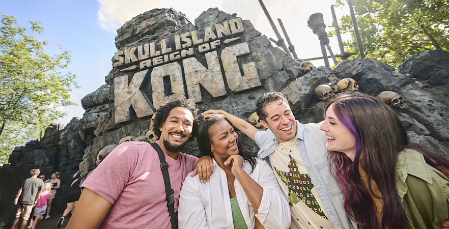 Guests smiling in front of Skull Island: Reign of Kong entrance at Universal Studios Orlando.