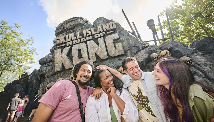 Guests smiling in front of Skull Island: Reign of Kong entrance at Universal Studios Orlando.