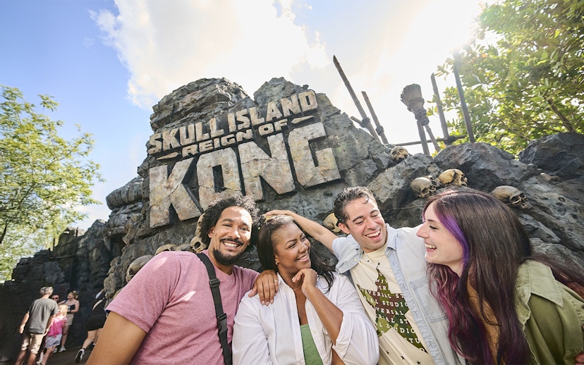 Guests smiling in front of Skull Island: Reign of Kong entrance at Universal Studios Orlando.