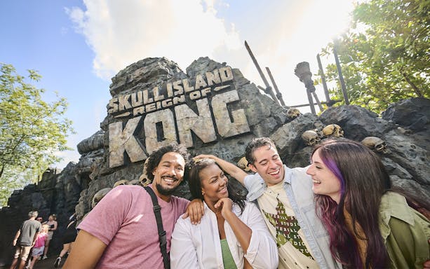 Guests smiling in front of Skull Island: Reign of Kong entrance at Universal Studios Orlando.
