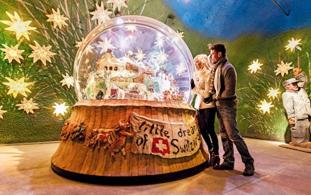 Couple admiring a large snow globe display at a museum in Jungfraujoch, Switzerland.