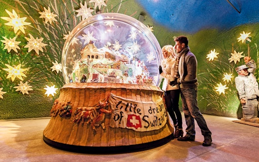Couple admiring a large snow globe display at a museum in Jungfraujoch, Switzerland.
