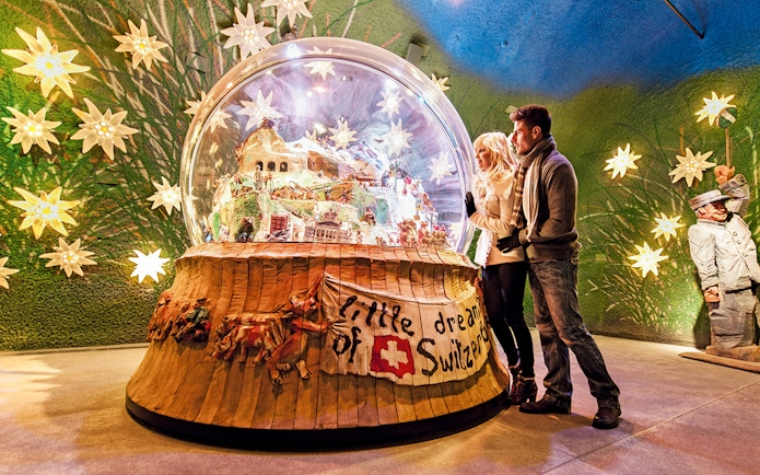 Couple admiring a large snow globe display at a museum in Jungfraujoch, Switzerland.
