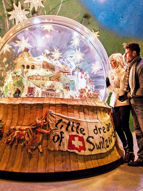 Couple admiring a large snow globe display at a museum in Jungfraujoch, Switzerland.