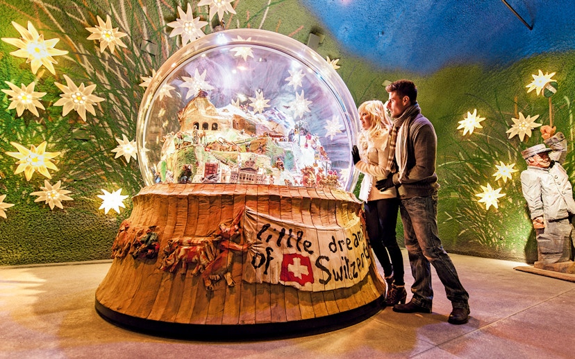 Couple admiring a large snow globe display at a museum in Jungfraujoch, Switzerland.