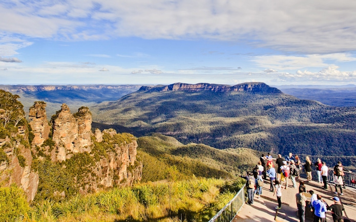 Visitors at Blue Mountains lookout with view of Three Sisters rock formation, Australia.