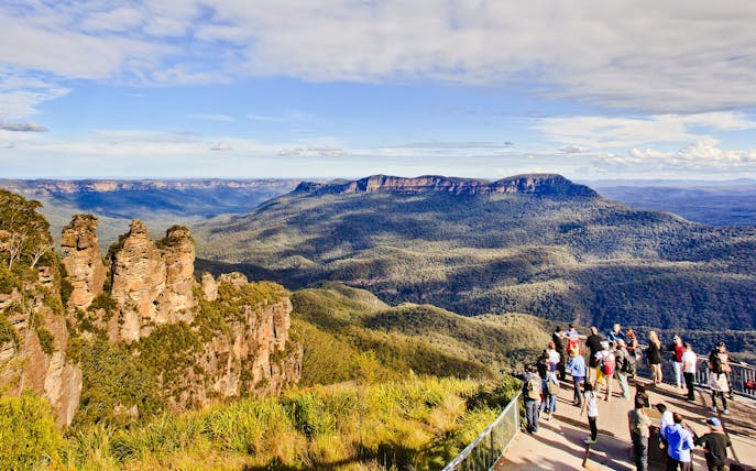 Visitors at Blue Mountains lookout with view of Three Sisters rock formation, Australia.