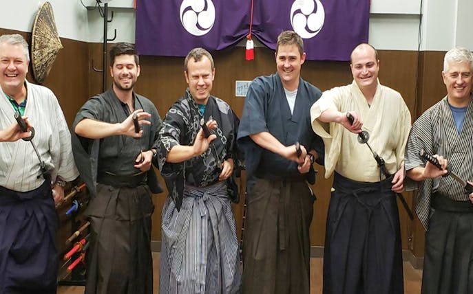 Participants in traditional samurai attire practicing sword techniques in Tokyo.