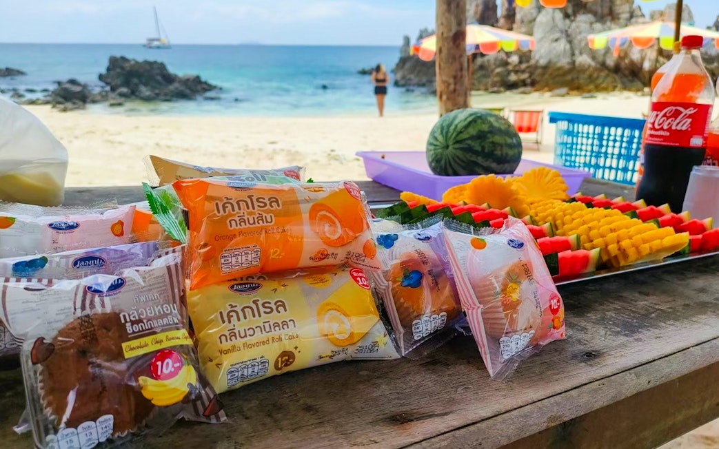 Snacks and fruit platter on a beach table during Phi Phi, Maya, and Khai Island speedboat tour from Phuket.