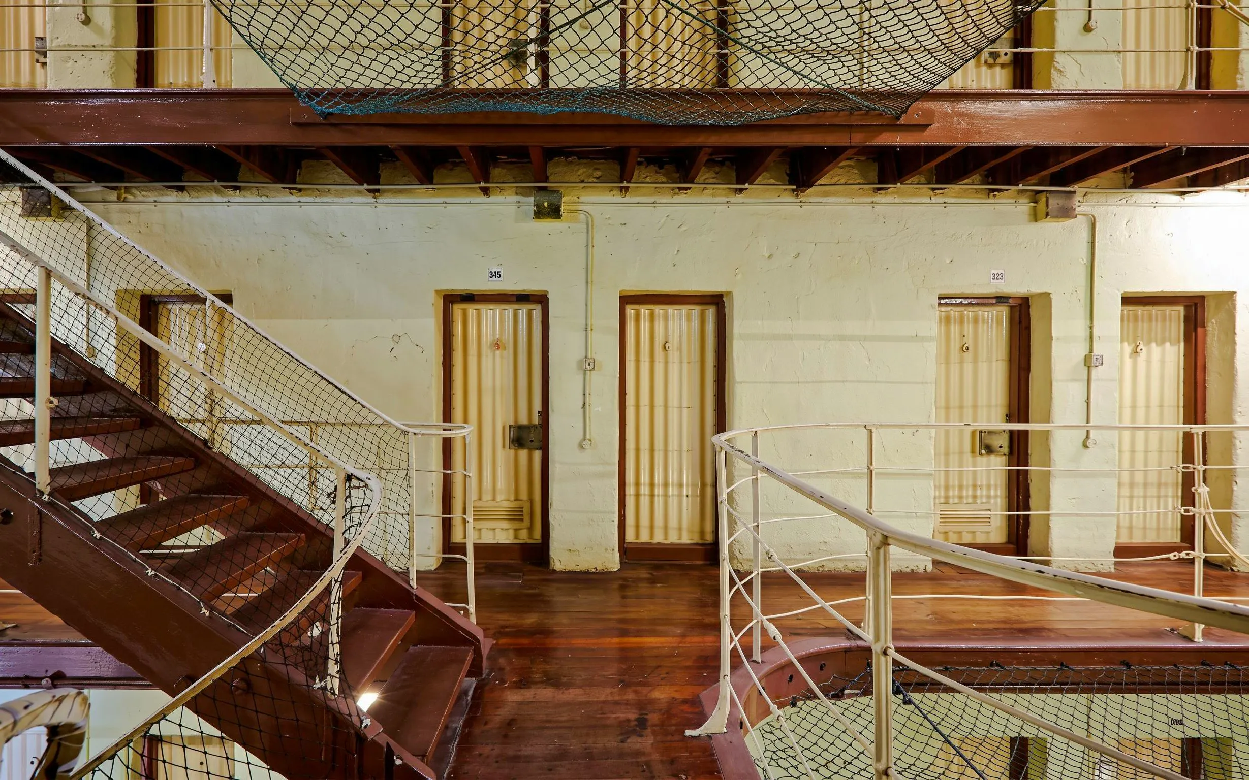 Fremantle Prison interior with cell doors and metal staircase.