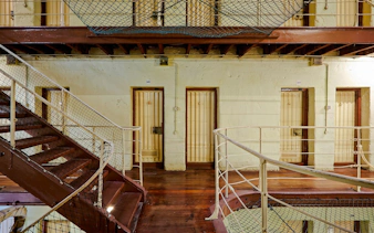 Fremantle Prison interior with cell doors and metal staircase.