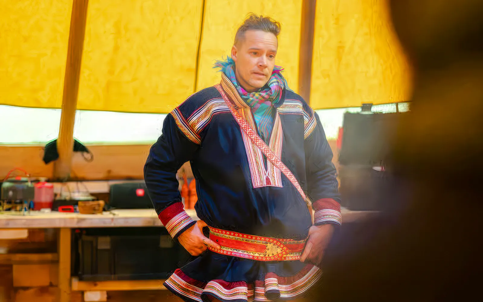 Sami person in traditional clothing inside a tent during Tromsø reindeer feeding tour.