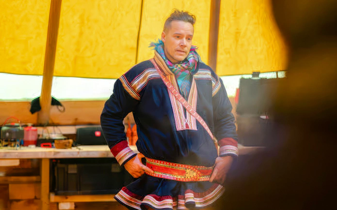 Sami person in traditional clothing inside a tent during Tromsø reindeer feeding tour.