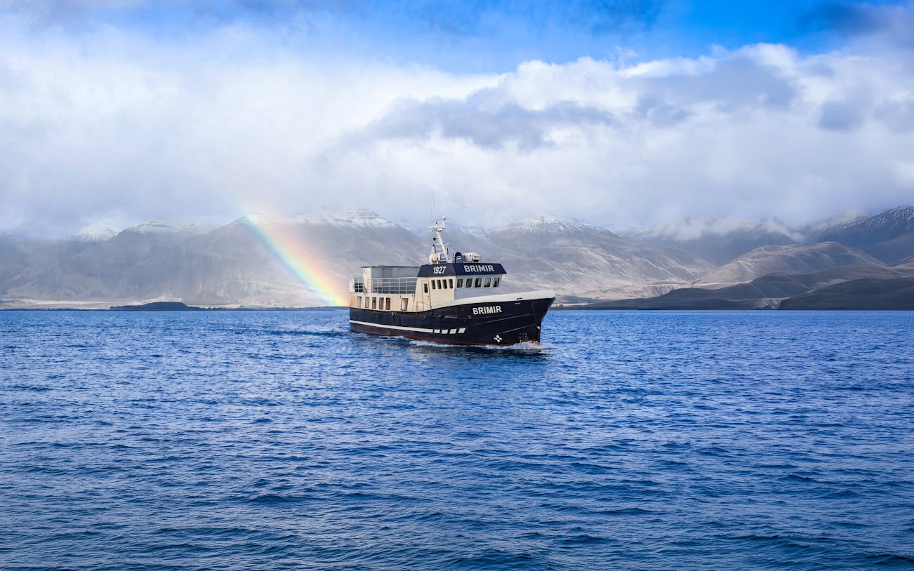 Boat on Eyjafjörður with rainbow, Akureyri whale watching tour.