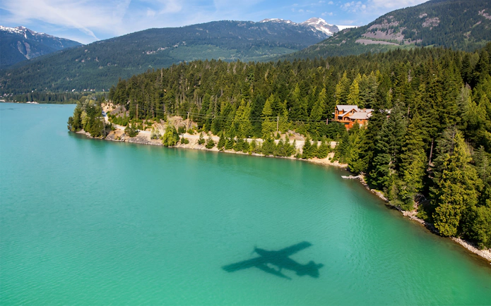 Seaplane shadow over turquoise lake during Whistler Glacier Seaplane Sightseeing Tour.