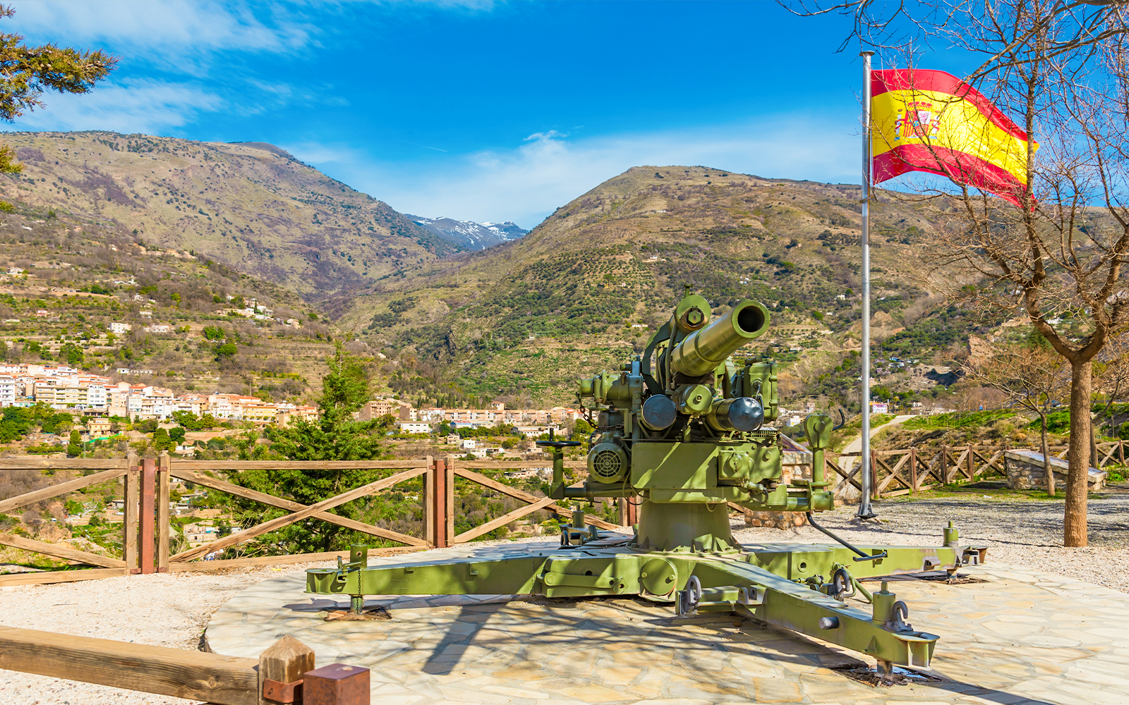 Cannon and Spanish flag at Visillo viewpoint, Lanjaron, Granada, with mountain backdrop.