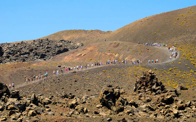 Tourists hiking on Nea Kameni volcano trail in Santorini, Greece.