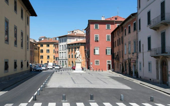 Pisa city square with colorful buildings and a central statue, ideal for a self-guided exploration game.