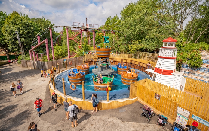 Visitors enjoying a spinning barrel ride at Chessington theme park main area.