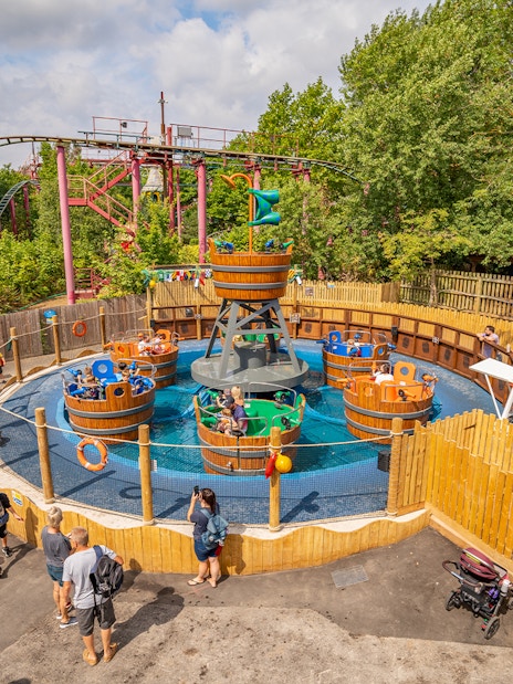 Visitors enjoying a spinning barrel ride at Chessington theme park main area.
