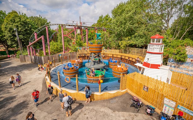Visitors enjoying a spinning barrel ride at Chessington theme park main area.