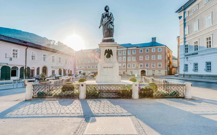 Mozart statue in Salzburg's Mozartplatz with surrounding historic buildings.