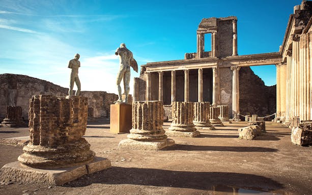 Ancient ruins and statues at Pompeii archaeological site on a sunny day.