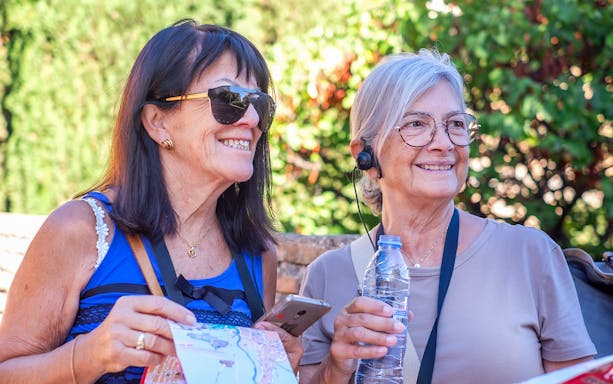 Tourists enjoying a small group tour at Alhambra, holding a map and wearing audio guides.
