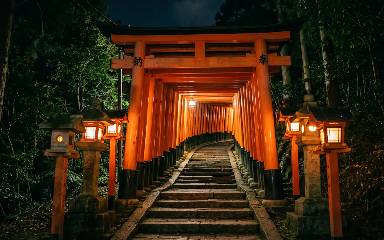 Lantern-lit torii gate path at Fushimi Inari, Kyoto, during a night walk.