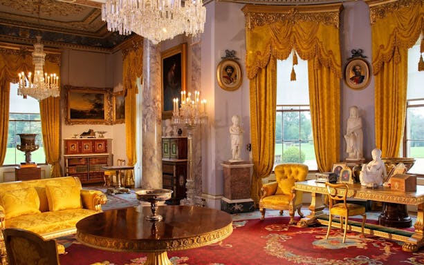 Osborne House interior with ornate chandeliers, yellow drapes, and classical statues.