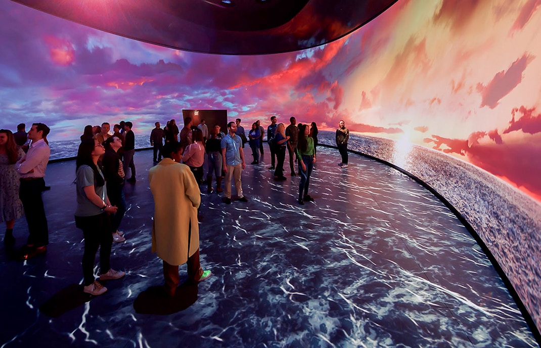 American Museum of Natural History exhibit featuring illuminated globe and visitors exploring displays.