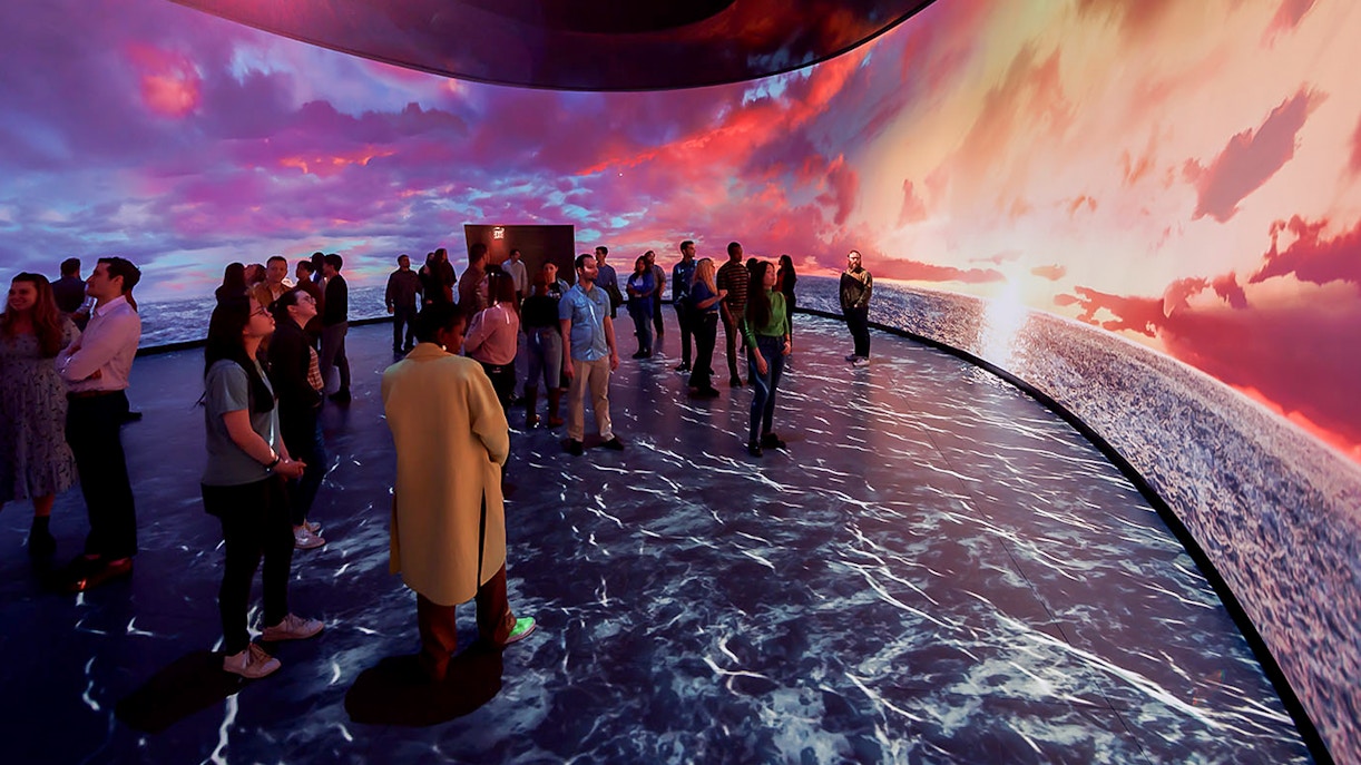 American Museum of Natural History exhibit featuring illuminated globe and visitors exploring displays.