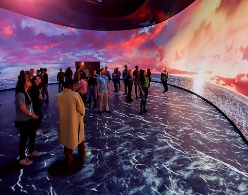 American Museum of Natural History exhibit featuring illuminated globe and visitors exploring displays.