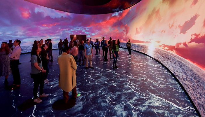 American Museum of Natural History exhibit featuring illuminated globe and visitors exploring displays.