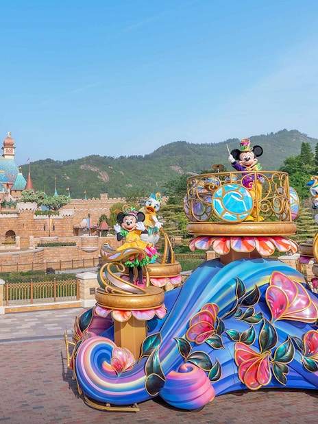 Parade float with characters in front of castle at Disneyland Hong Kong.