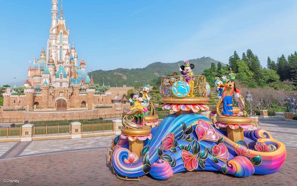 Parade float with characters in front of castle at Disneyland Hong Kong.