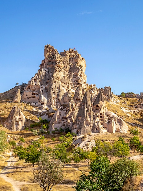 Uchisar Castle rock formations in Cappadocia, Turkey, under a clear blue sky.